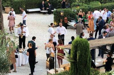 Salle de réception avec des invités assis à des tables, éclairée par des guirlandes lumineuses suspendues.