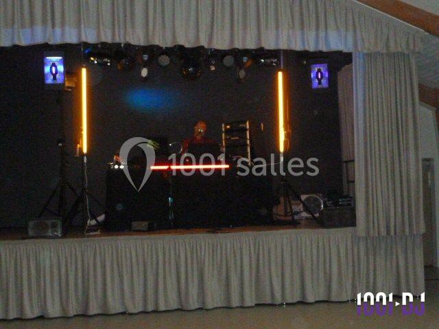 Un DJ mixe sur une scène éclairée par des lumières colorées, entouré d'équipements audio et visuels.