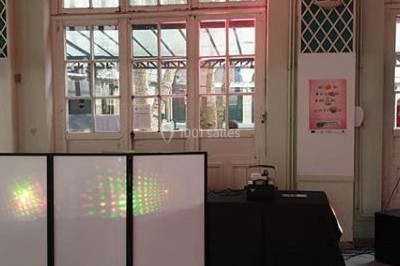 Installation de matériel de sonorisation et éclairage dans une salle avec grandes fenêtres et carrelage au sol.