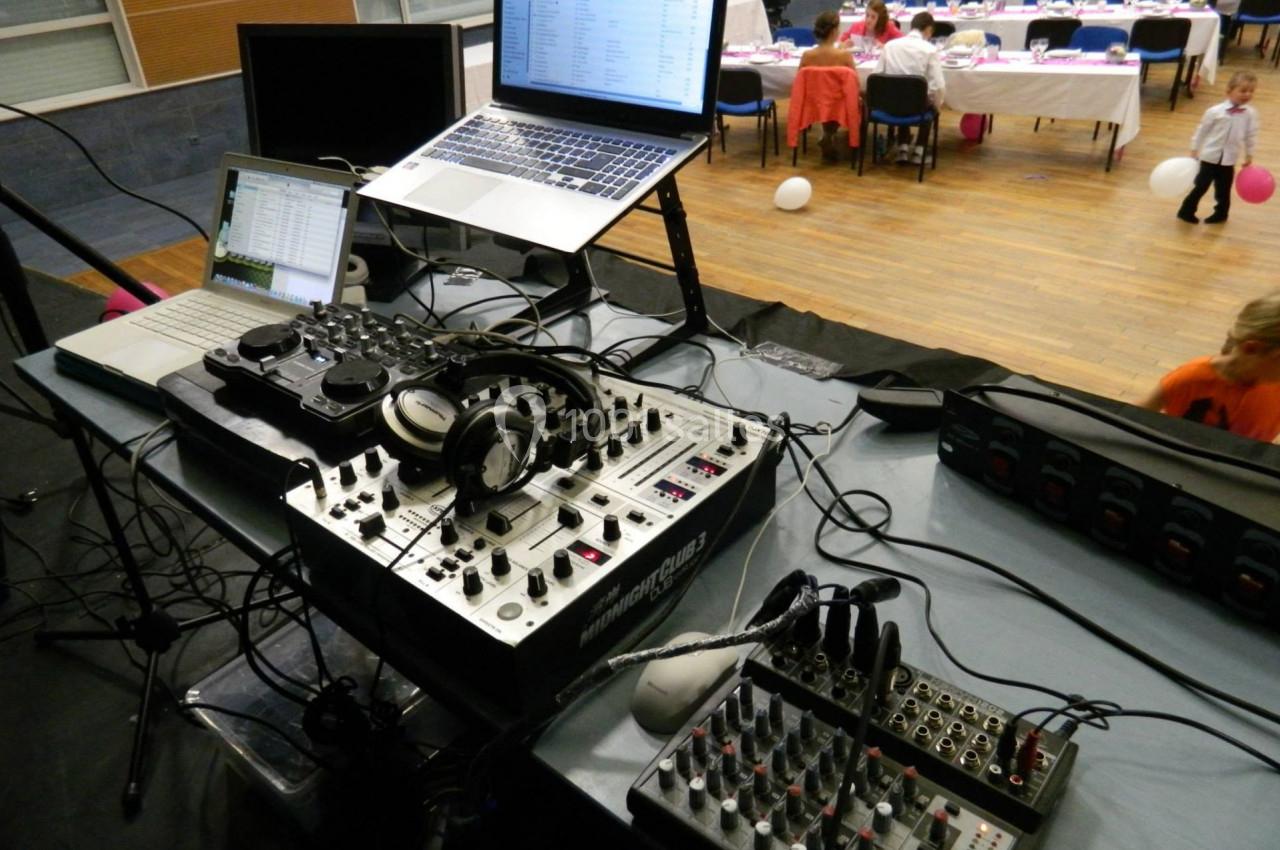 Matériel de DJ avec platines, table de mixage et ordinateurs, installé sur une scène lors d'un événement festif.