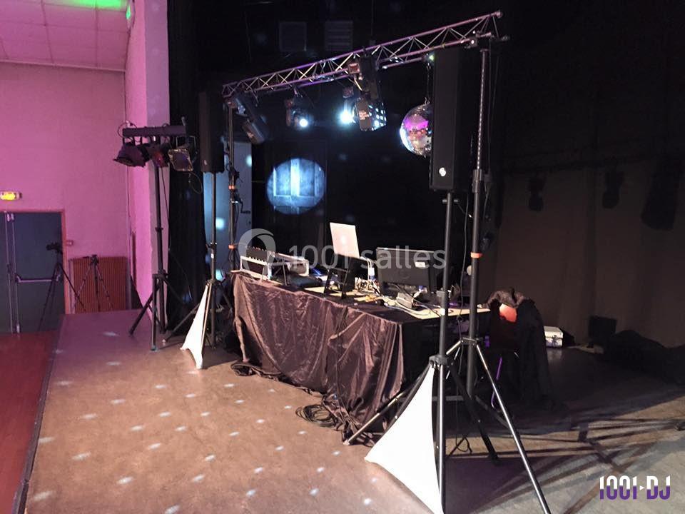 Installation de matériel de sonorisation et d'éclairage sur une scène, avec une table de mixage et des projecteurs.