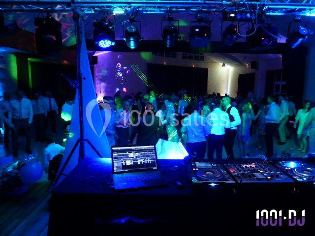 Vue d'une piste de danse animée avec des lumières colorées, observée depuis une table de mixage équipée.