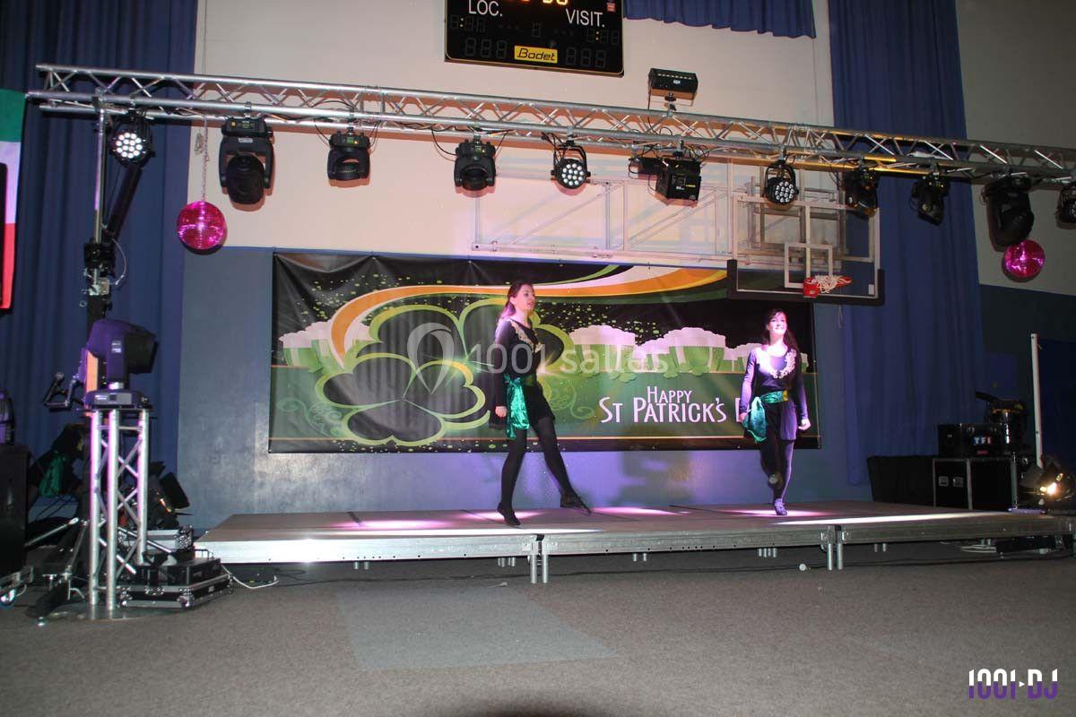 Deux danseuses exécutent une performance sur scène décorée pour la Saint-Patrick, éclairée par des projecteurs.