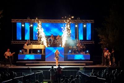 Salle avec éclairage de scène coloré, piste de danse illuminée, tables sur les côtés et matériel audio en arrière-plan.