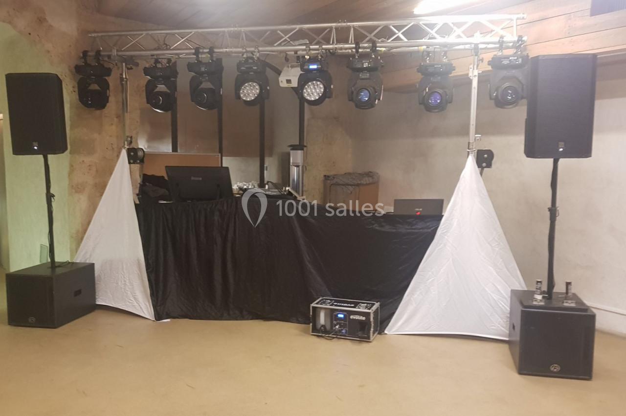 Installation de matériel de sonorisation et éclairage avec une table de mixage dans une salle intérieure.