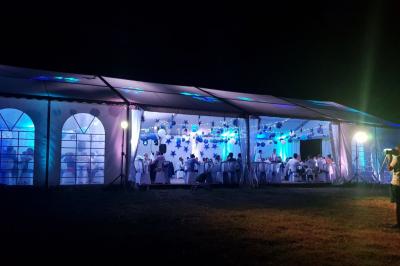 Salle avec éclairage de scène coloré, piste de danse illuminée, tables sur les côtés et matériel audio en arrière-plan.