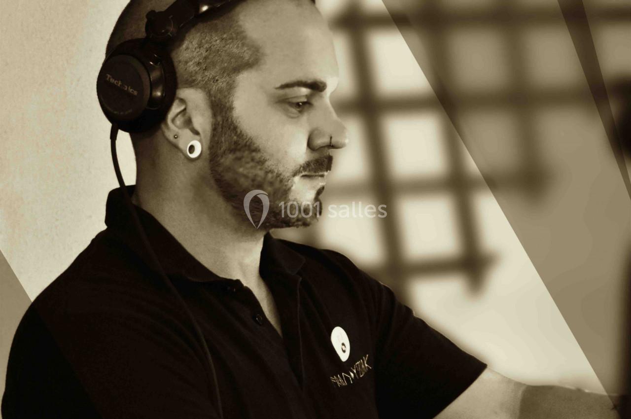 Un DJ concentré mixe de la musique avec un casque audio, dans une ambiance aux tons sépia.