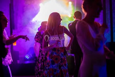Deux femmes dansent et discutent dans une ambiance festive avec des lumières colorées.