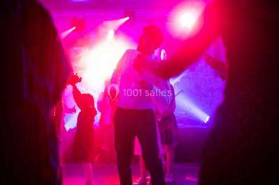 Deux femmes dansent et discutent dans une ambiance festive avec des lumières colorées.