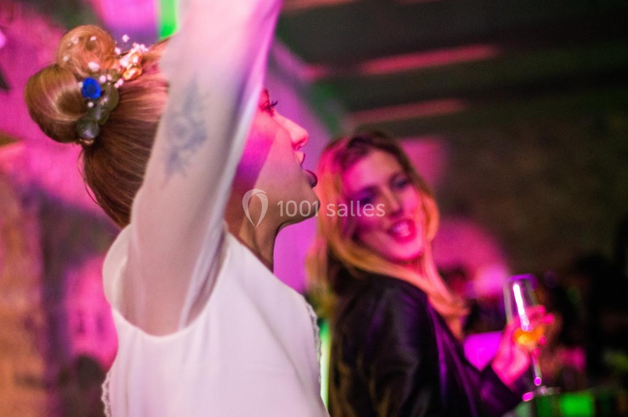 Deux femmes dansent et discutent dans une ambiance festive avec des lumières colorées.