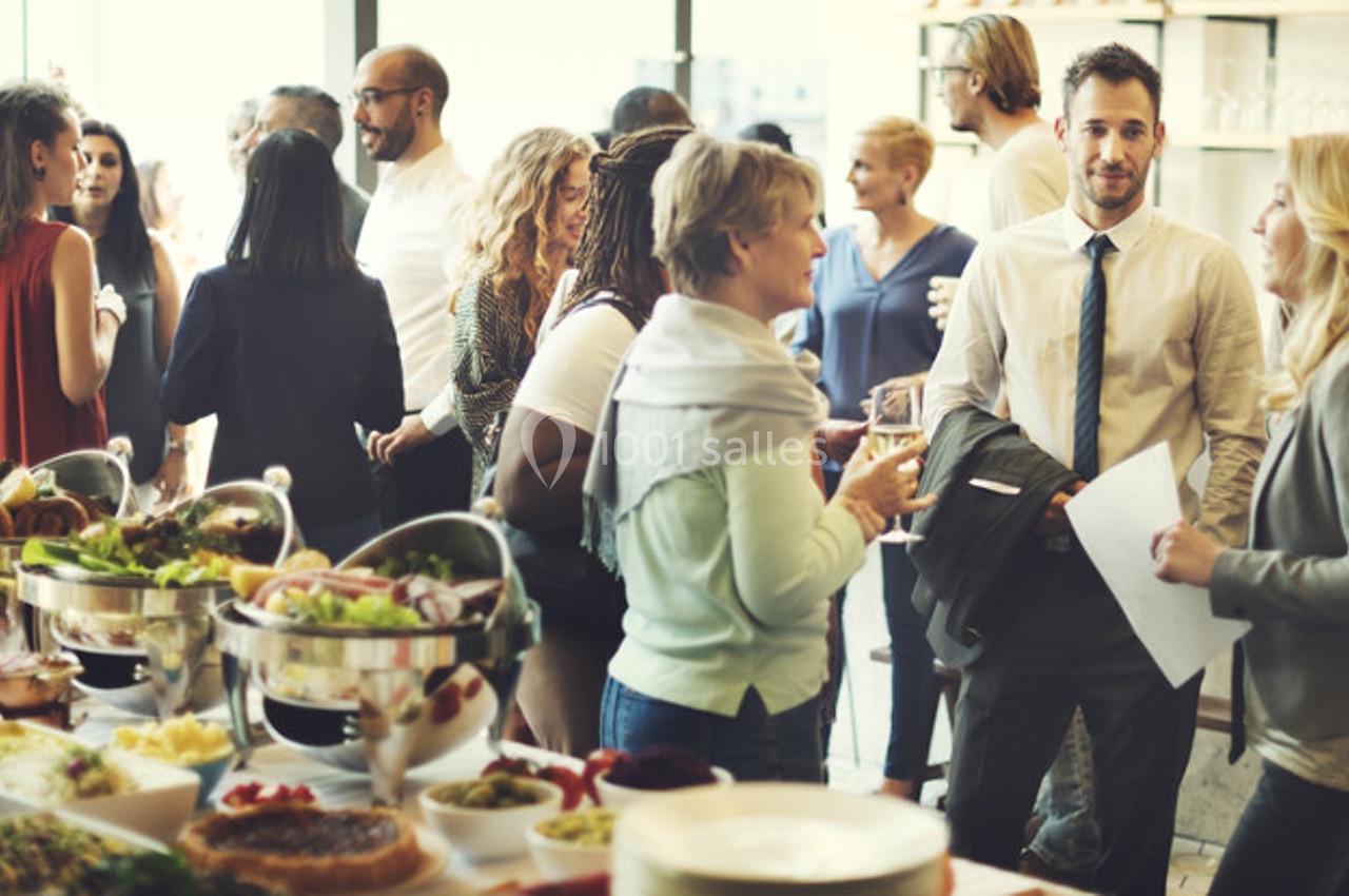 Des personnes discutent debout lors d'un événement avec un buffet de plats variés au premier plan.