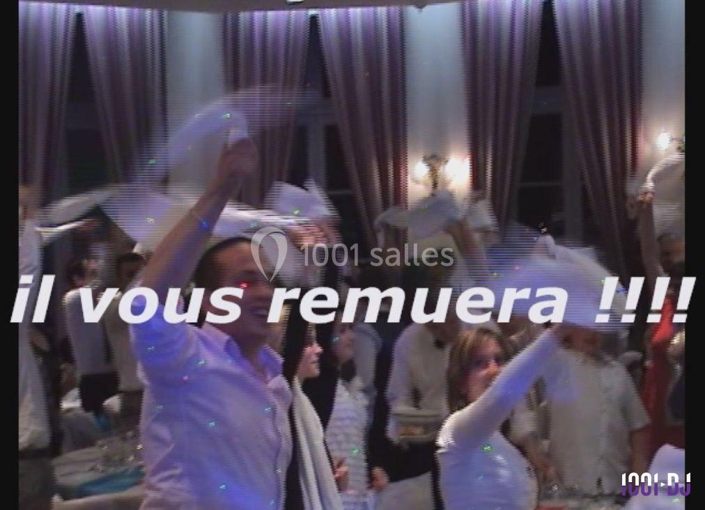 Des personnes dansent en agitant des serviettes blanches dans une salle éclairée par des rideaux et des lumières tamisées.