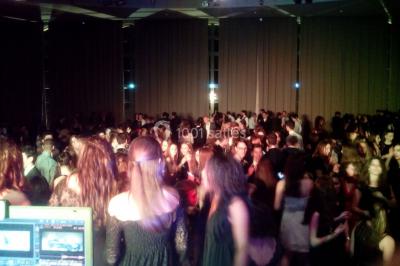 Des personnes souriantes lèvent les bras et posent devant un écran dans une ambiance festive en intérieur.