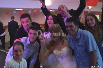 Des personnes souriantes lèvent les bras et posent devant un écran dans une ambiance festive en intérieur.