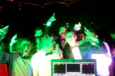 Des personnes souriantes lèvent les bras et posent devant un écran dans une ambiance festive en intérieur.