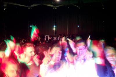 Des personnes souriantes lèvent les bras et posent devant un écran dans une ambiance festive en intérieur.