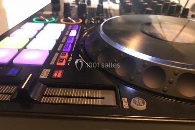 Des personnes dansent et lèvent les bras dans une ambiance festive, éclairée par des lumières colorées.