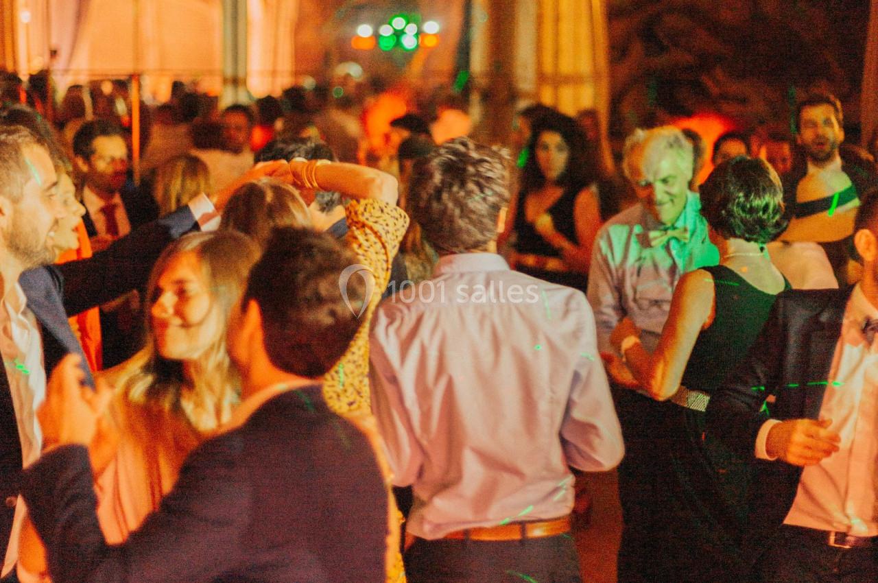Personnes dansant et discutant lors d'une soirée animée, éclairée par des lumières colorées.