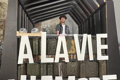 Des personnes dansent et lèvent les bras dans une ambiance festive, éclairée par des lumières colorées.