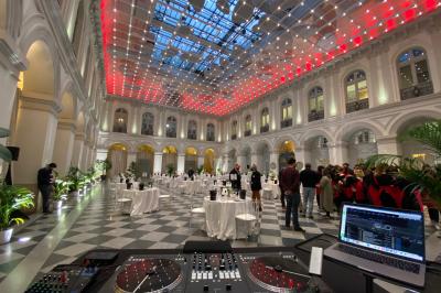 Des personnes dansent et lèvent les bras dans une ambiance festive, éclairée par des lumières colorées.