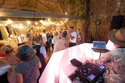 Des invités dansent et célèbrent sous une tente décorée, autour d'une mariée et d'un homme en costume.