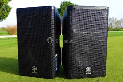 Des invités dansent et célèbrent sous une tente décorée, autour d'une mariée et d'un homme en costume.