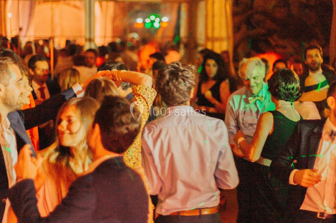 Personnes dansant et discutant lors d'une soirée animée avec éclairages colorés en intérieur.