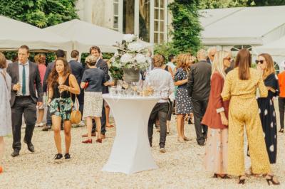Des invités dansent et célèbrent sous une tente décorée, autour d'une mariée et d'un homme en costume.