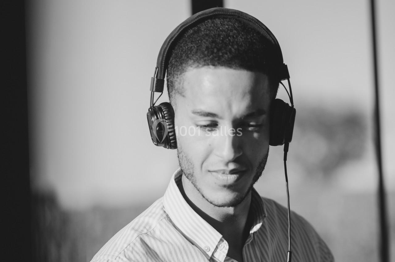 Un homme portant un casque audio, capturé en noir et blanc, avec un arrière-plan flou.