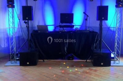 Salle décorée avec un sapin de Noël, éclairages colorés au sol et matériel de DJ installé sur une estrade.