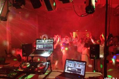 Un DJ portant un casque mixe de la musique sur une table de mixage dans un environnement extérieur couvert.