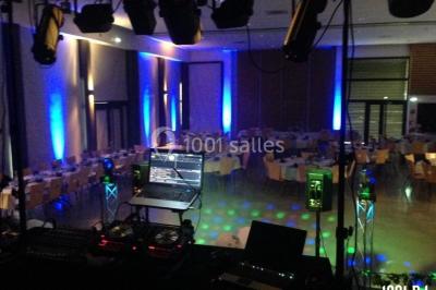 Un DJ portant un casque mixe de la musique sur une table de mixage dans un environnement extérieur couvert.