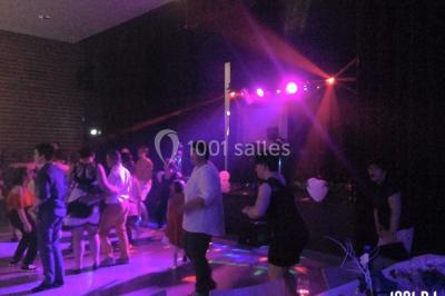 Un DJ portant un casque mixe de la musique sur une table de mixage dans un environnement extérieur couvert.