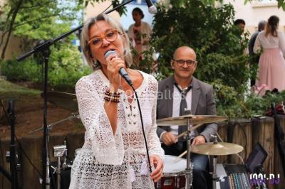 Un DJ portant un casque mixe de la musique sur une table de mixage dans un environnement extérieur couvert.