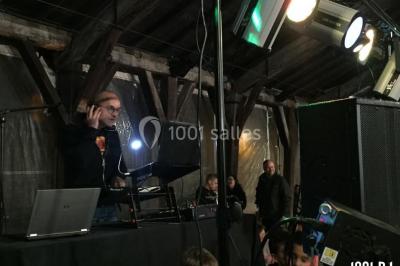 Un DJ portant un casque mixe de la musique sur une table de mixage dans un environnement extérieur couvert.