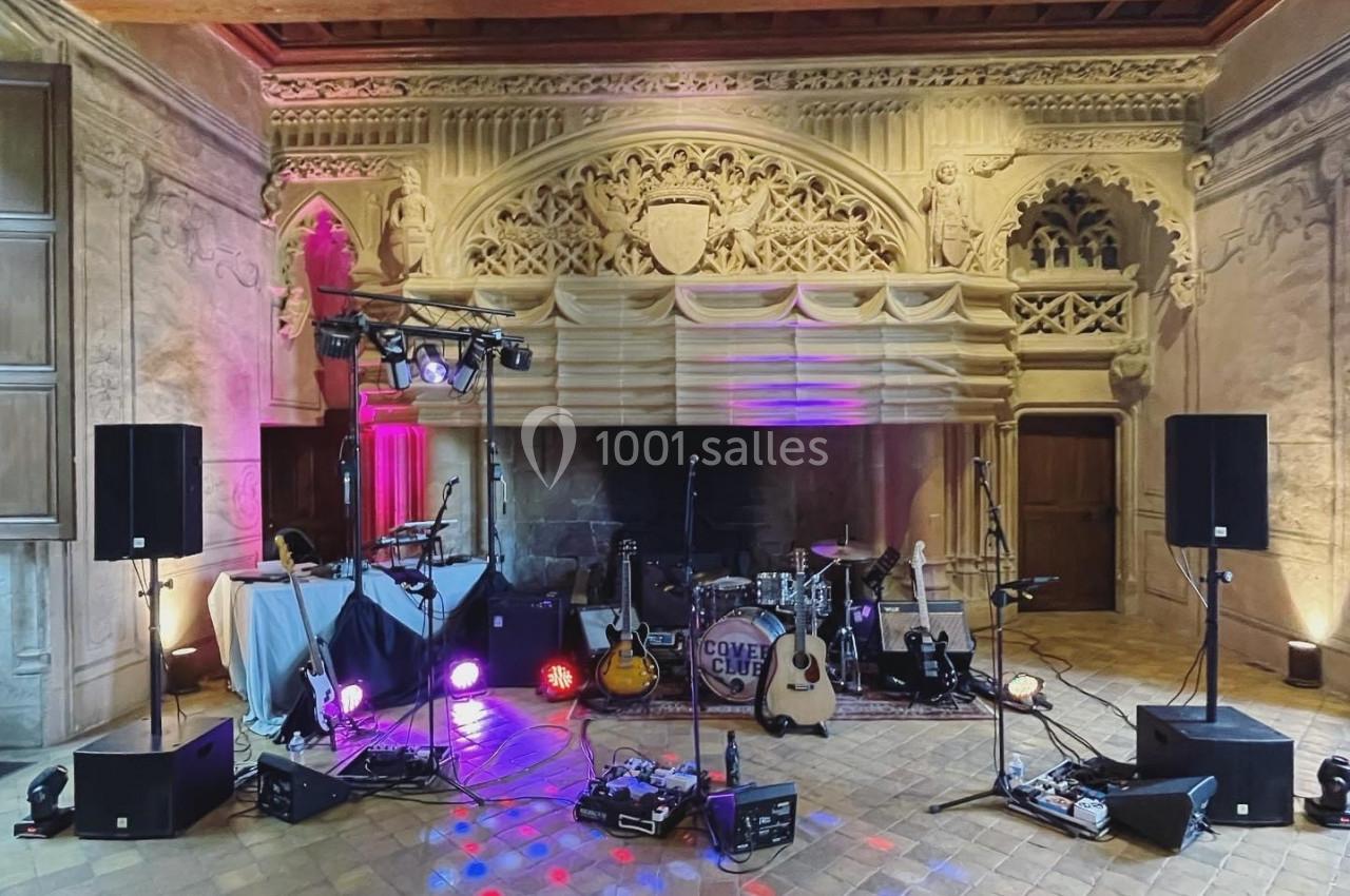 Scène musicale installée dans une salle au décor ancien avec instruments, éclairages et équipements audio.