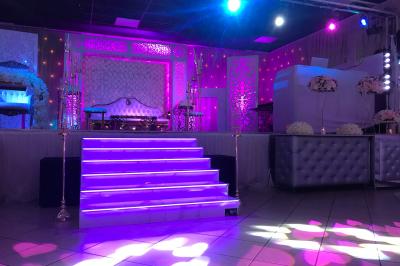 Un DJ portant un casque mixe de la musique sur une table de mixage dans un environnement extérieur couvert.