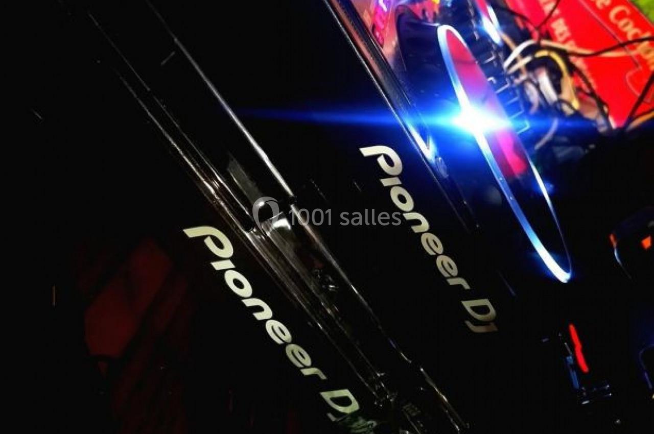 Platines DJ Pioneer illuminées dans un environnement sombre, avec des lumières colorées et des détails lumineux.