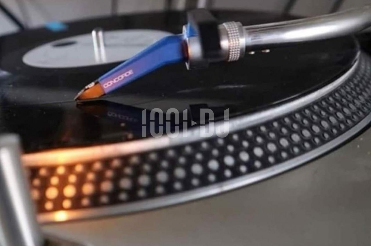 Bras de lecture bleu d'une platine vinyle en train de lire un disque noir, avec un éclairage chaud.