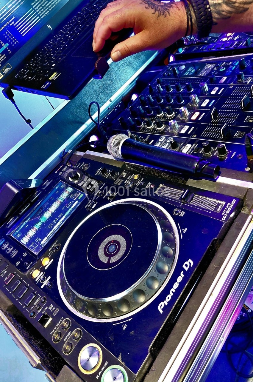 Table de mixage DJ avec platine, microphone et ordinateur portable en arrière-plan.