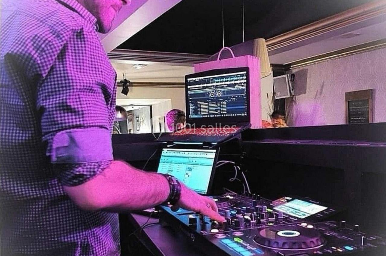 Un DJ mixant de la musique sur une table de mixage dans un environnement lumineux avec un ordinateur portable ouvert.