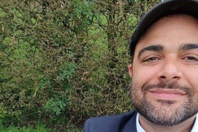 Un homme et une femme sourient devant un fond décoré de feuillage et de rideaux blancs.