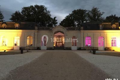 Façade d'un grand bâtiment éclairé par des lumières rouges et oranges dans un environnement nocturne.