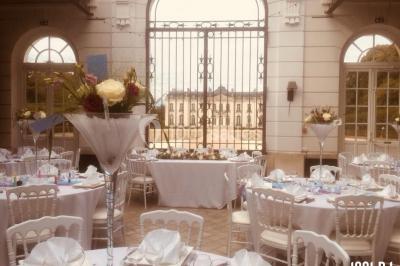 Table ronde décorée pour un événement, avec nappes blanches, chemin de table rose et bleu, et vaisselle élégante.