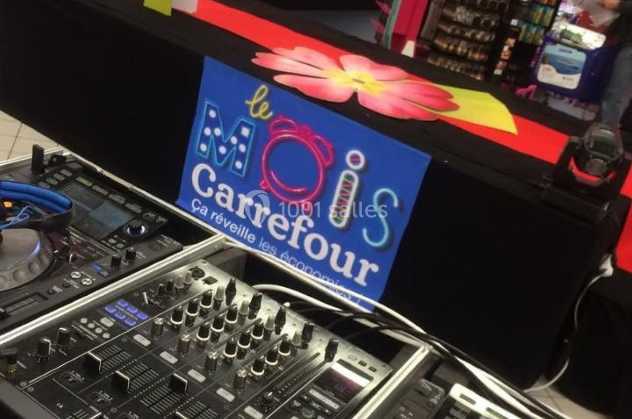 Poste de DJ avec platines et table de mixage installé dans un supermarché décoré pour une promotion.