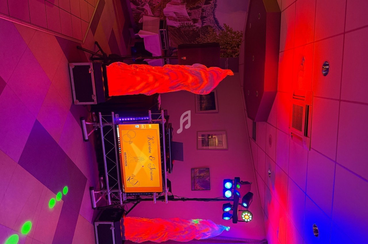 Installation de matériel de sonorisation et éclairage coloré dans une salle avec décor mural et plafond carrelé.
