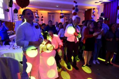 Homme portant des lunettes et un costume bleu, regardant légèrement sur le côté dans un environnement intérieur.