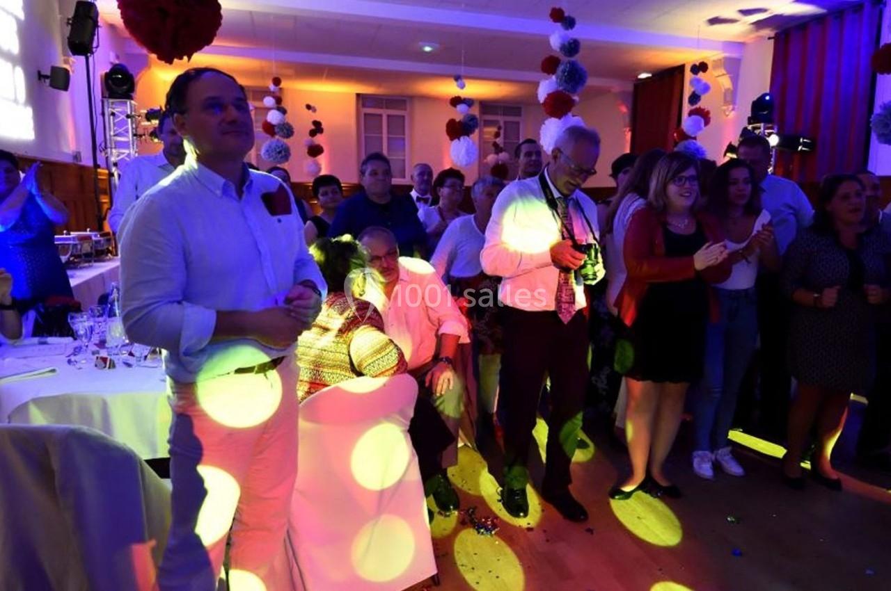 Groupe de personnes debout et assises dans une salle éclairée, observant une scène avec des lumières colorées.