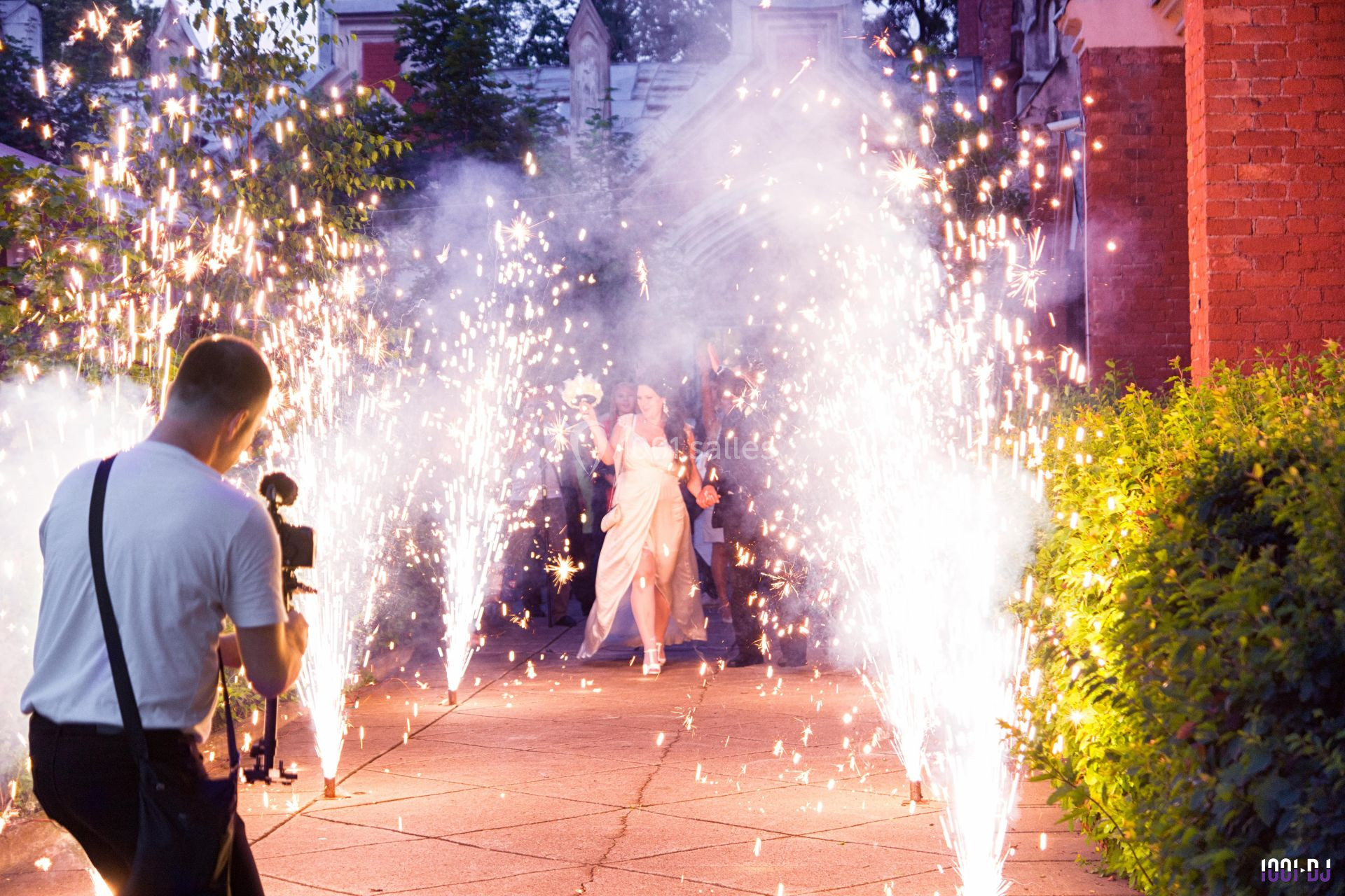 Un couple avance sous des gerbes d'étincelles lors d'une célébration, photographié par un professionnel.