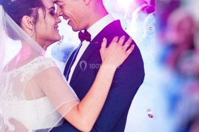 Une femme en robe blanche joue de la harpe dans une salle décorée avec des plantes et des lumières.
